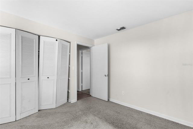 unfurnished bedroom featuring carpet floors, a closet, visible vents, and baseboards