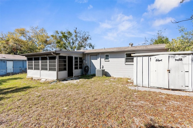 back of property featuring central AC unit, a sunroom, a yard, an outdoor structure, and a shed