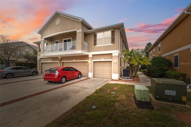 townhome / multi-family property with stucco siding, driveway, an attached garage, and central AC