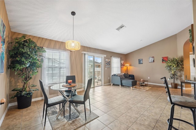 dining area with vaulted ceiling, light tile patterned floors, arched walkways, and visible vents