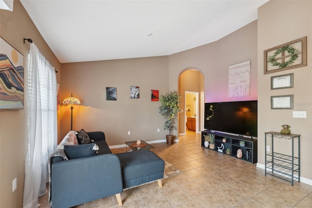 living room with arched walkways, tile patterned floors, lofted ceiling, and baseboards