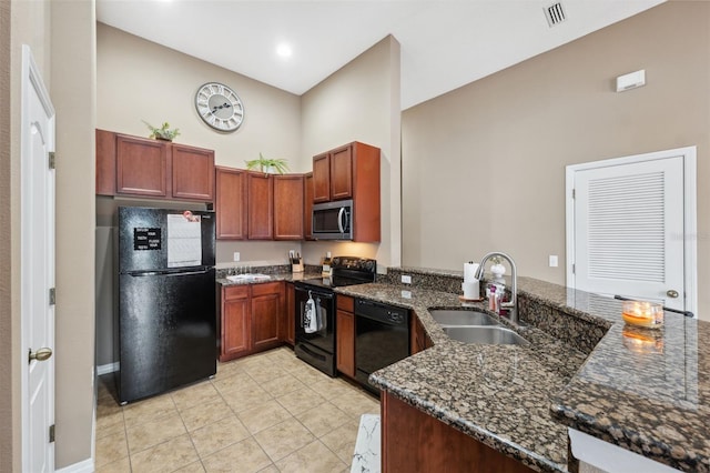 kitchen featuring visible vents, dark stone countertops, a peninsula, black appliances, and a sink