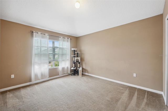 carpeted empty room featuring baseboards