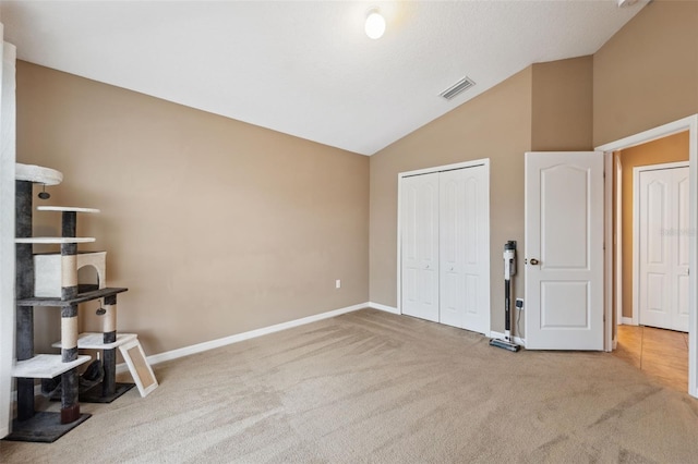 interior space featuring a closet, visible vents, carpet flooring, and lofted ceiling