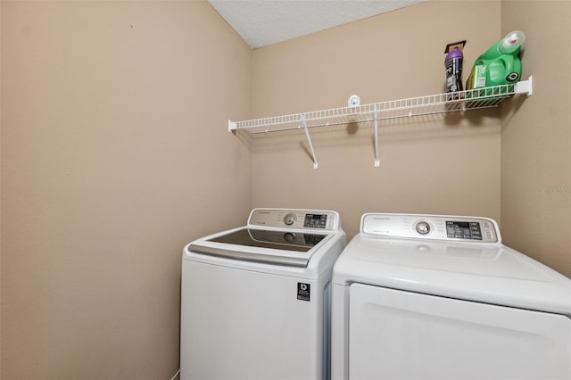 clothes washing area with a textured ceiling, washing machine and dryer, and laundry area