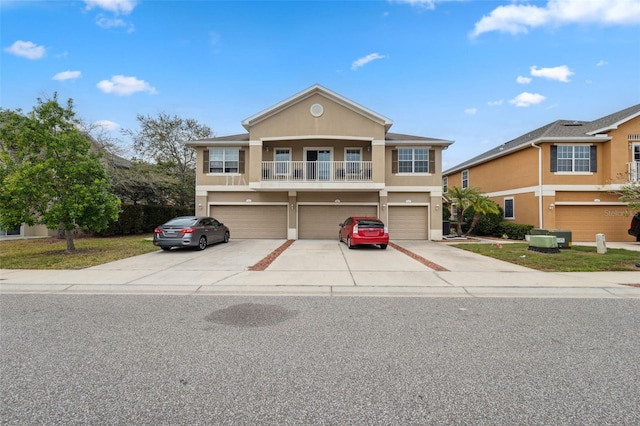 view of front of house with a balcony, driveway, stucco siding, a garage, and central air condition unit