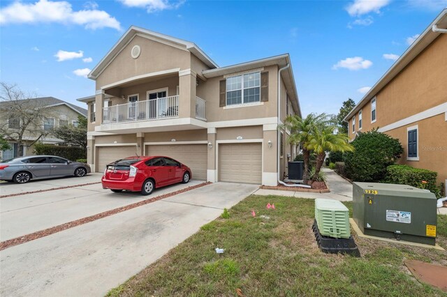 view of property featuring stucco siding, central AC unit, concrete driveway, and an attached garage