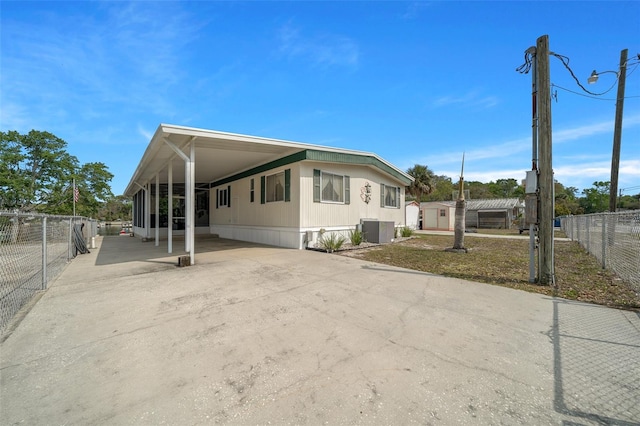 manufactured / mobile home with fence, central AC, a carport, concrete driveway, and a storage shed