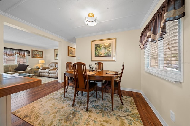 dining space featuring ornamental molding, baseboards, and wood finished floors