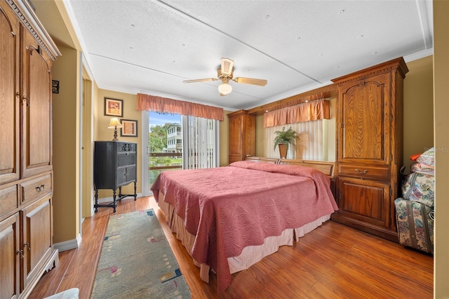 bedroom with a ceiling fan, crown molding, light wood finished floors, baseboards, and access to exterior