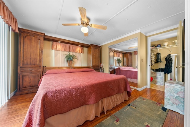 bedroom featuring a spacious closet, baseboards, light wood-type flooring, ornamental molding, and a closet