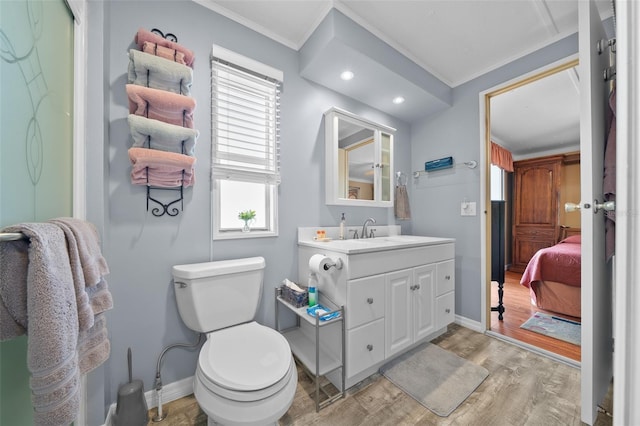 bathroom featuring toilet, ornamental molding, wood finished floors, baseboards, and vanity