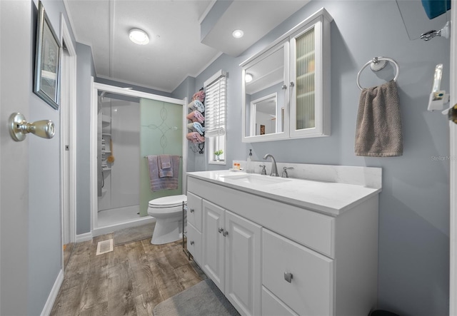 bathroom with visible vents, a shower stall, toilet, and wood finished floors