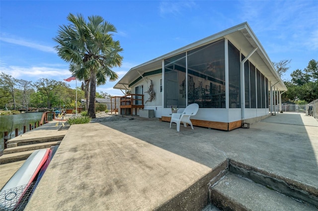 back of property with a water view and a sunroom