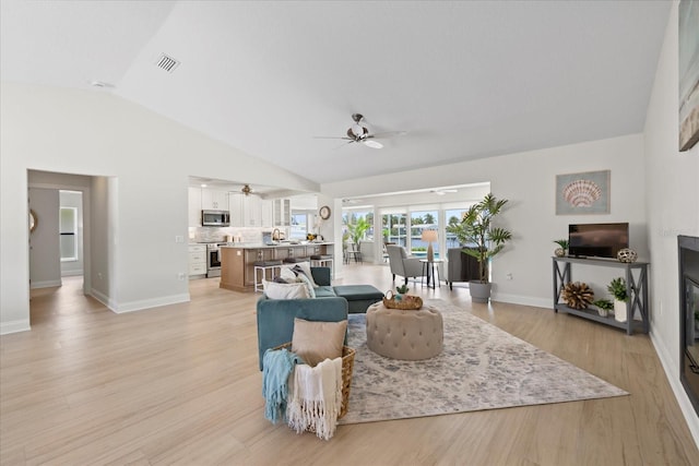 5000 Galleon Ct, New Port Richey, FL 34652 - living room featuring a ceiling fan, vaulted ceiling, and light wood-type flooring