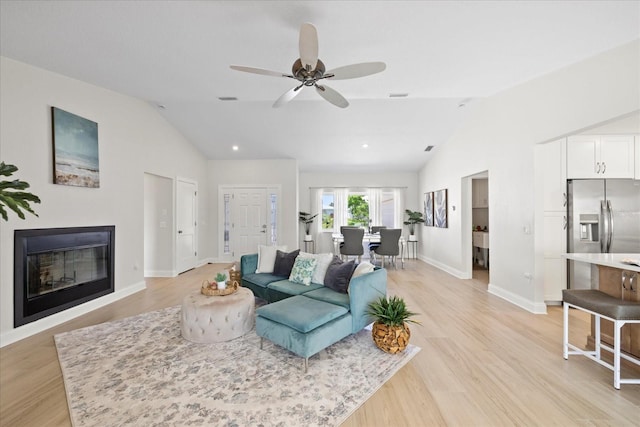 5000 Galleon Ct, New Port Richey, FL 34652 - living room with vaulted ceiling, a glass covered fireplace, light wood-type flooring, a ceiling fan, and recessed lighting