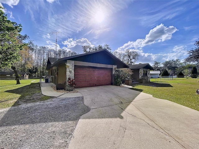 view of front of home with concrete driveway, an attached garage, fence, stone siding, and a front lawn