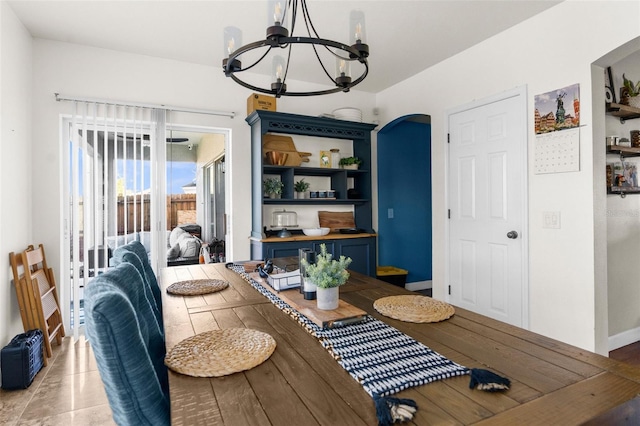 dining space featuring light wood-style flooring, baseboards, arched walkways, and a chandelier