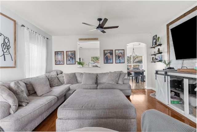 living room featuring arched walkways, a healthy amount of sunlight, ceiling fan, and wood finished floors