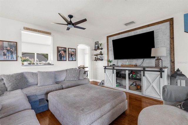 living room with arched walkways, visible vents, ceiling fan, and wood finished floors