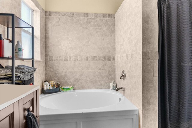 bathroom featuring curtained shower, vanity, and a tub