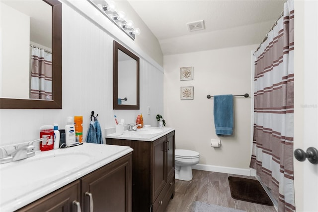 bathroom with toilet, wood finished floors, visible vents, and a sink