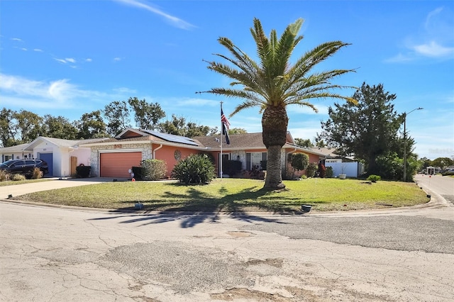 ranch-style house with roof mounted solar panels, fence, a garage, driveway, and a front lawn