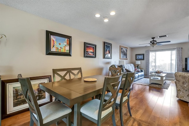 dining room with visible vents, a textured ceiling, and hardwood / wood-style floors