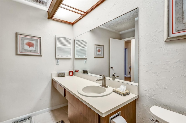 bathroom featuring baseboards, visible vents, a textured wall, toilet, and vanity