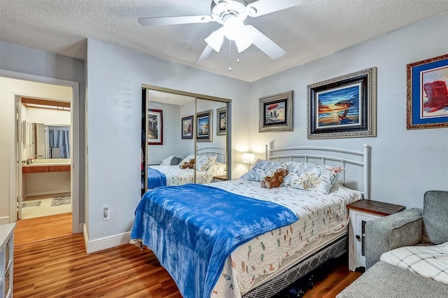 bedroom with a closet, ceiling fan, a textured ceiling, wood finished floors, and baseboards