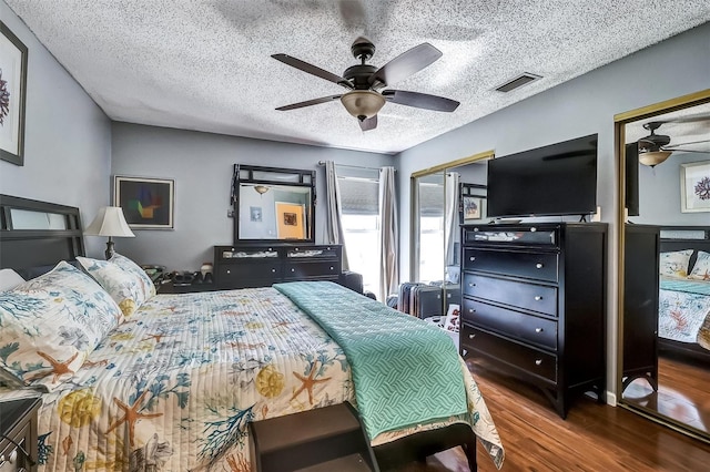 bedroom featuring a textured ceiling, ceiling fan, wood finished floors, and visible vents