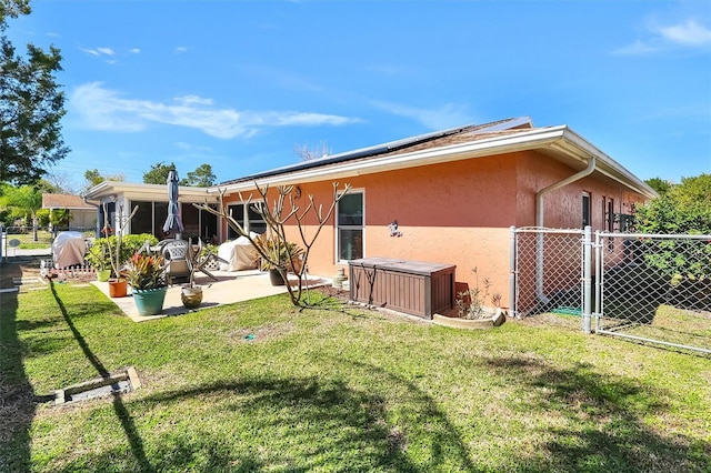 rear view of house featuring fence, a lawn, a gate, stucco siding, and a patio area