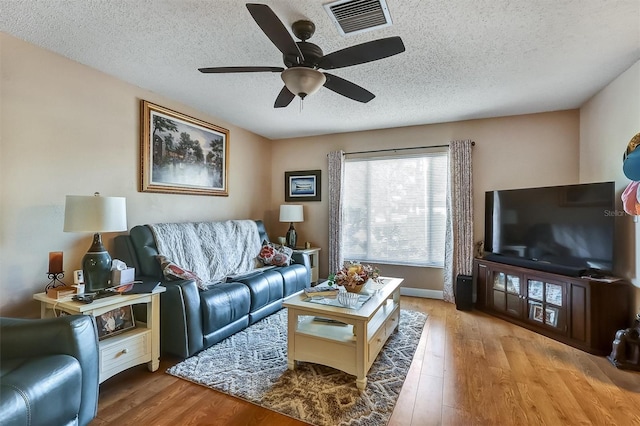 living area featuring a textured ceiling, wood finished floors, and visible vents