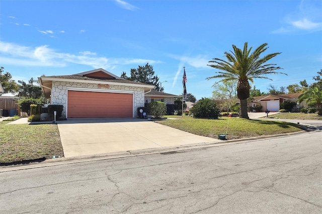 view of front of property with a garage, stone siding, a front lawn, and driveway