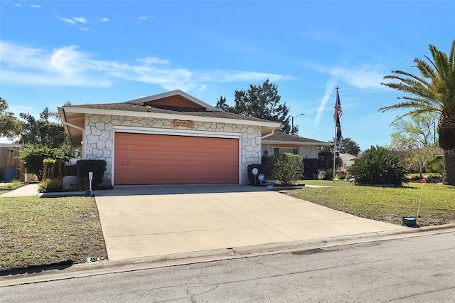 ranch-style house featuring stone siding, concrete driveway, a front lawn, and an attached garage