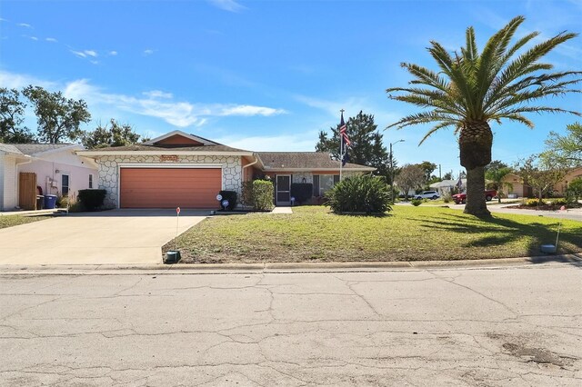 single story home with an attached garage, concrete driveway, stone siding, and a front yard