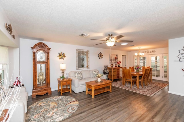 living room with dark wood-style floors, visible vents, a textured ceiling, baseboards, and ceiling fan with notable chandelier