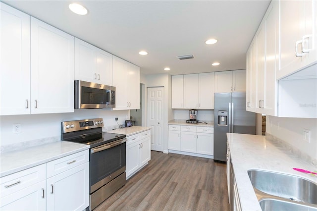 kitchen featuring recessed lighting, stainless steel appliances, wood finished floors, a sink, and visible vents