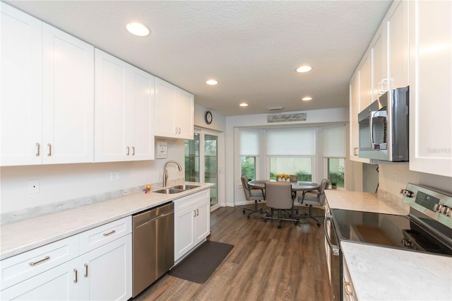 kitchen with stainless steel appliances, dark wood-style flooring, white cabinetry, and a sink