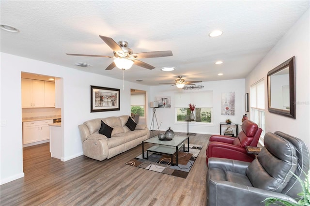 living area with recessed lighting, a textured ceiling, baseboards, and wood finished floors