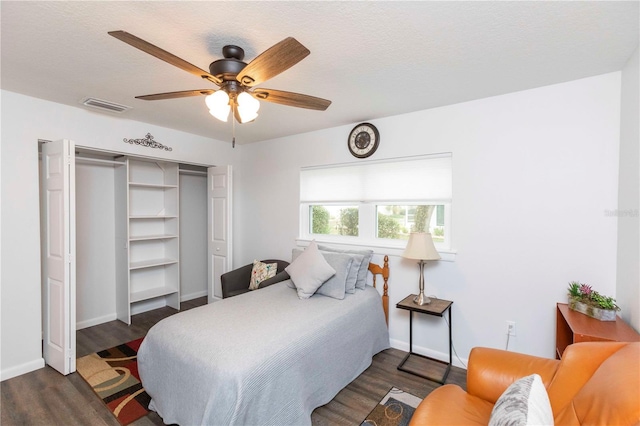 bedroom with a closet, visible vents, a ceiling fan, wood finished floors, and baseboards