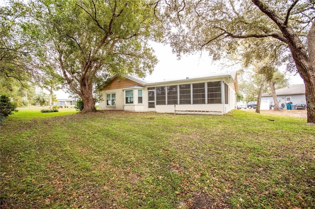 rear view of property with a sunroom and a yard