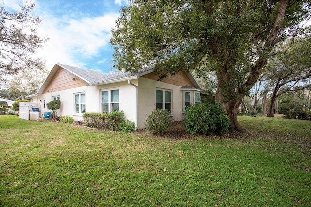 view of side of home featuring a lawn and stucco siding