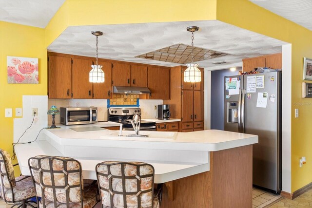 5441 Alderwood St, Spring Hill, FL 34606 - kitchen featuring tasteful backsplash, light countertops, appliances with stainless steel finishes, a peninsula, and under cabinet range hood