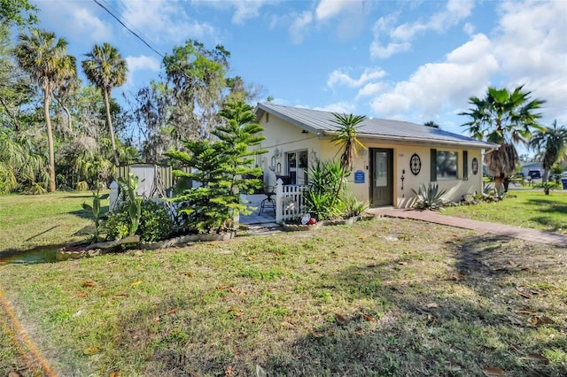 view of front of house featuring a front yard, metal roof, an outdoor structure, and stucco siding