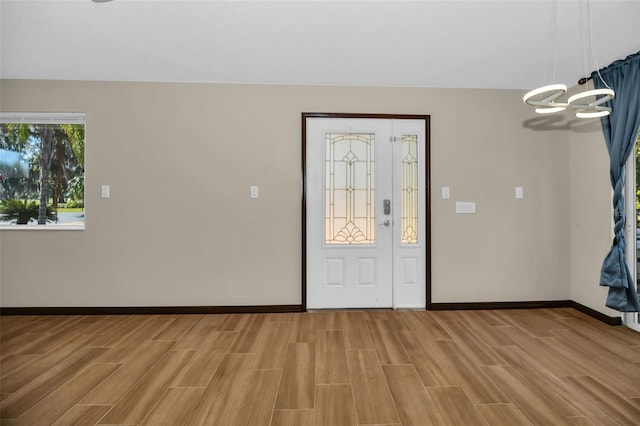 foyer featuring wood finish floors, baseboards, and a notable chandelier