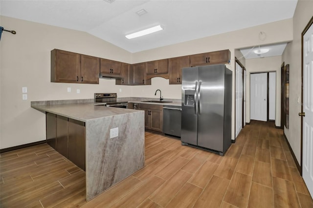 kitchen featuring wood tiled floor, a peninsula, a sink, appliances with stainless steel finishes, and under cabinet range hood