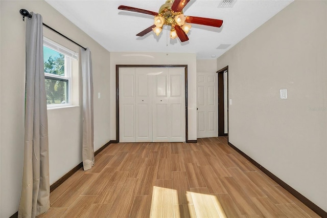 unfurnished bedroom featuring wood finish floors, visible vents, a ceiling fan, a closet, and baseboards