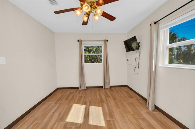 spare room with wood tiled floor, visible vents, baseboards, and ceiling fan