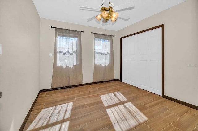 unfurnished bedroom with a ceiling fan, baseboards, a closet, and wood tiled floor